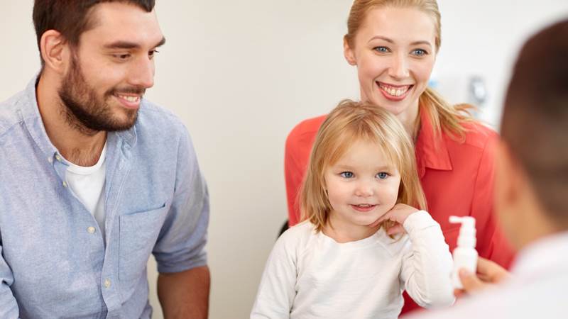 En pappa , en mamma  och en liten flicka sitter och samtalar med en läkare